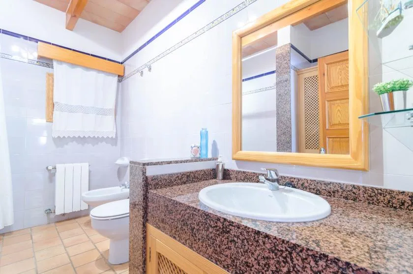 Un baño alicatado con lavabo, espejo, inodoro y radiador.