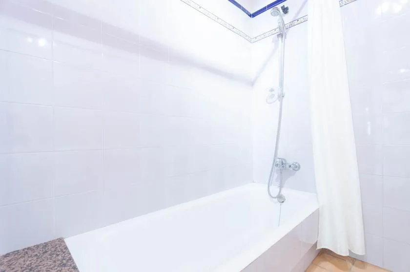Un baño alicatado con bañera y cortina de ducha.