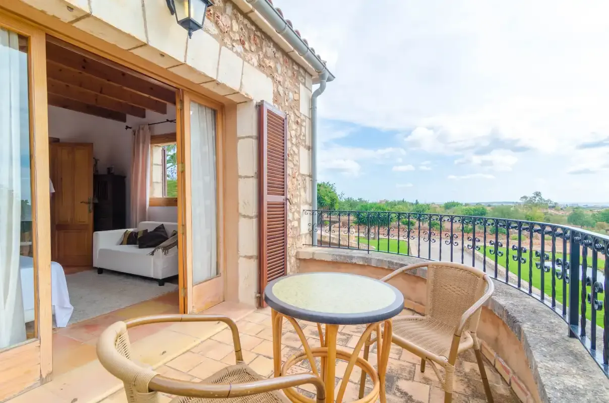 Una casa de piedra da a una terraza con asientos y vistas al campo.