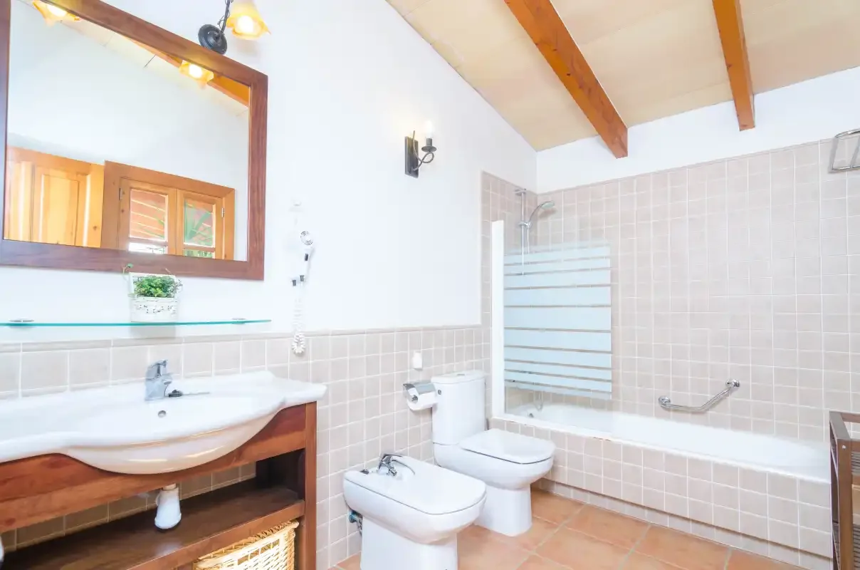 Un baño alicatado con lavabo, inodoro, bidé y ducha de cristal.