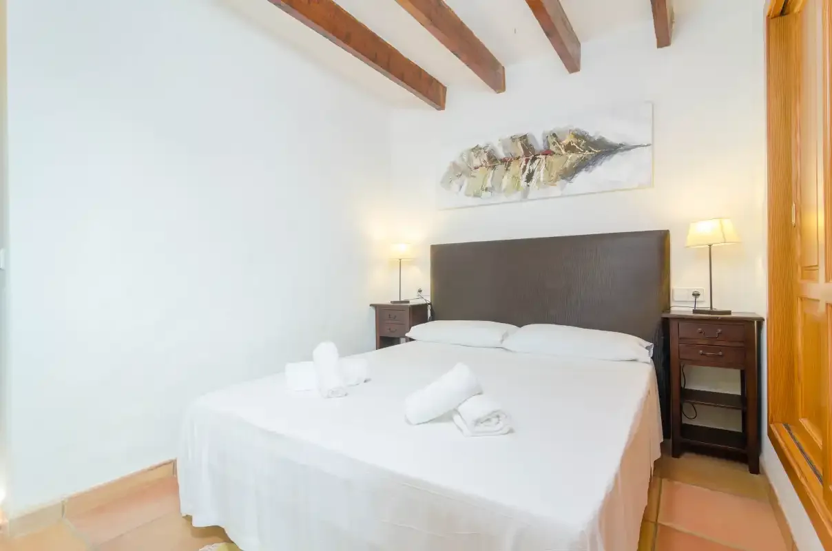 Un dormitorio con una cama bien hecha y vigas de madera a la vista.