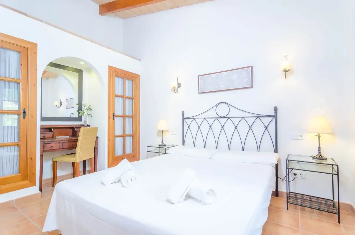 Un dormitorio luminoso con una cama grande y puertas con marcos de madera.