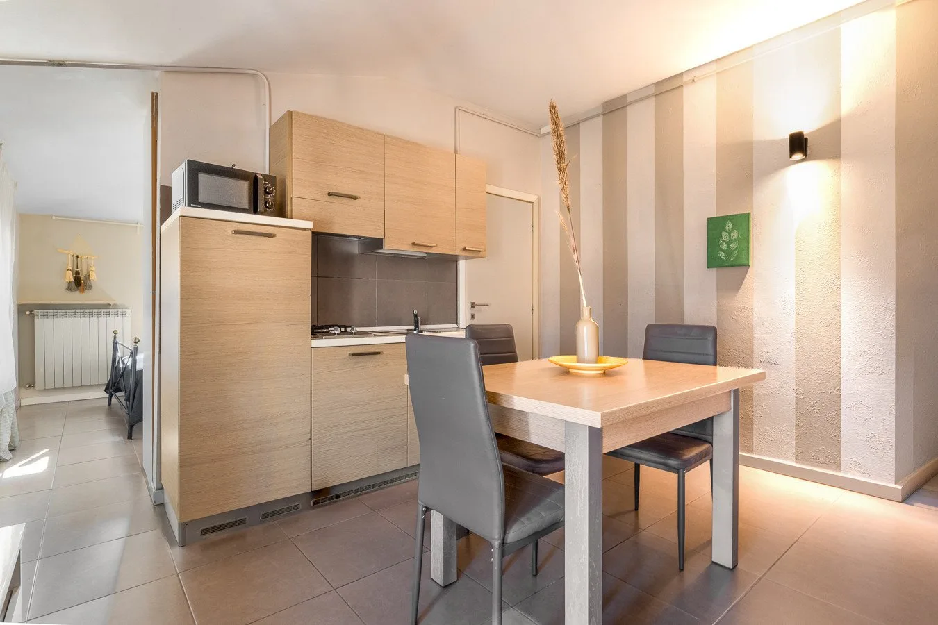 Una cocina compacta con zona de comedor, muebles de madera clara y una mesa.