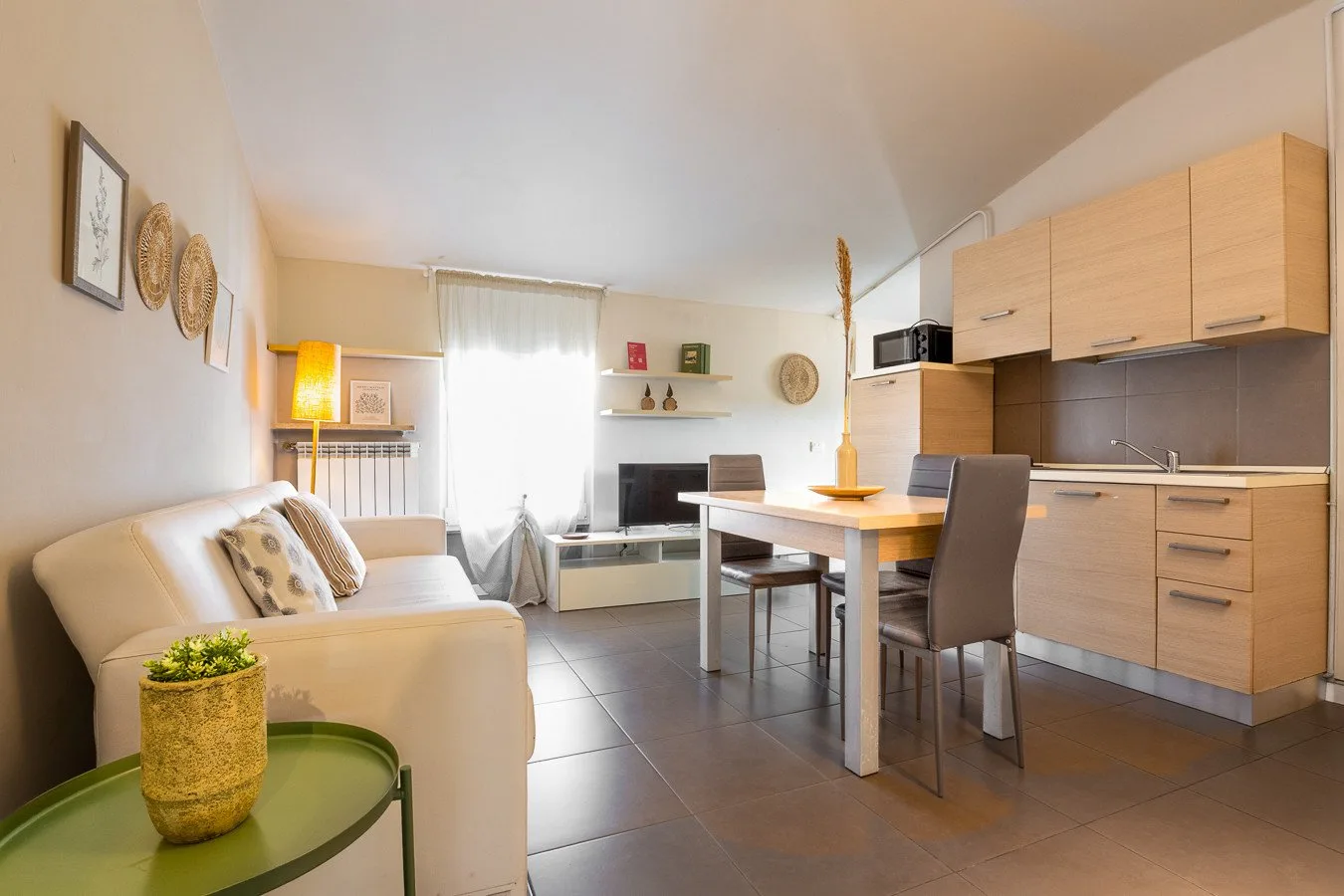 Una luminosa sala-comedor con sofá, mesa y armarios de cocina.