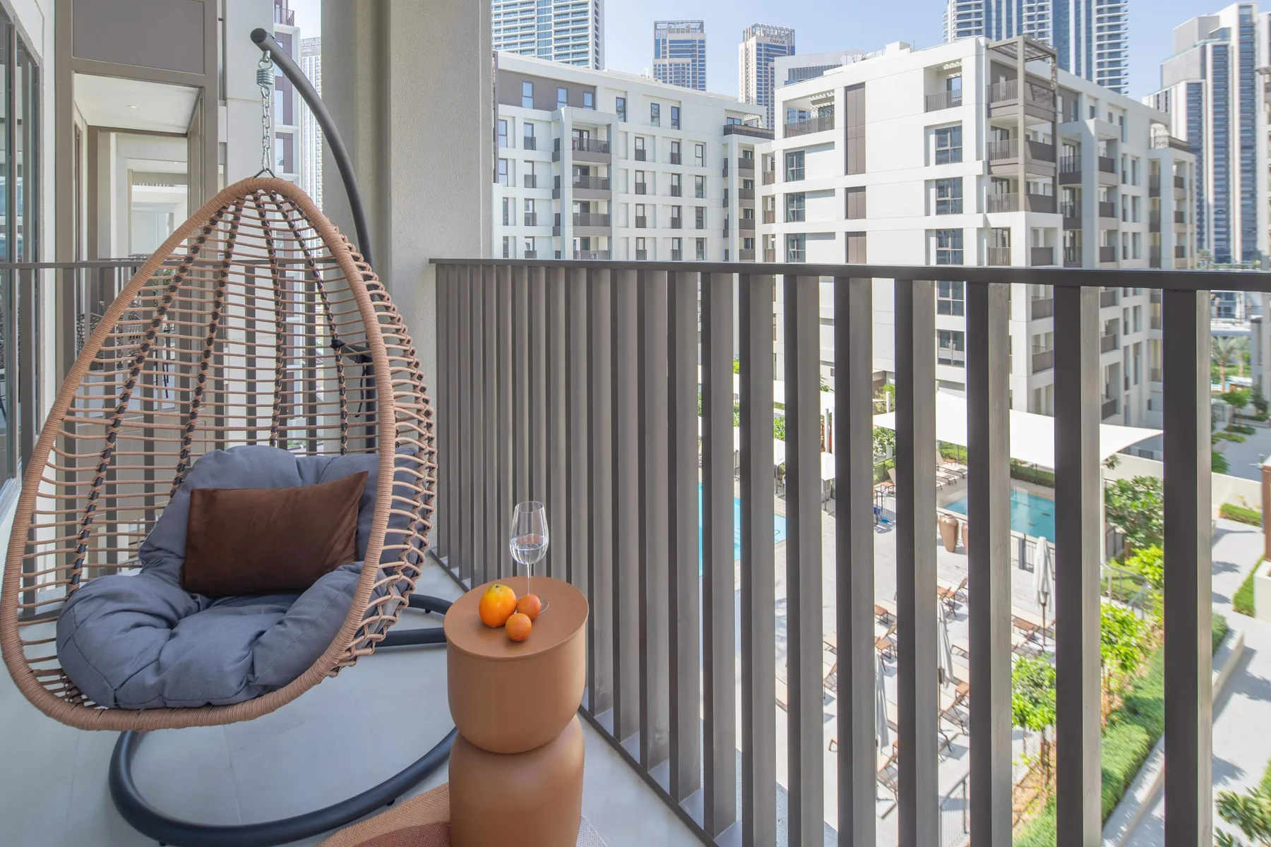 Un balcón con un asiento colgante y vistas a edificios cercanos.
