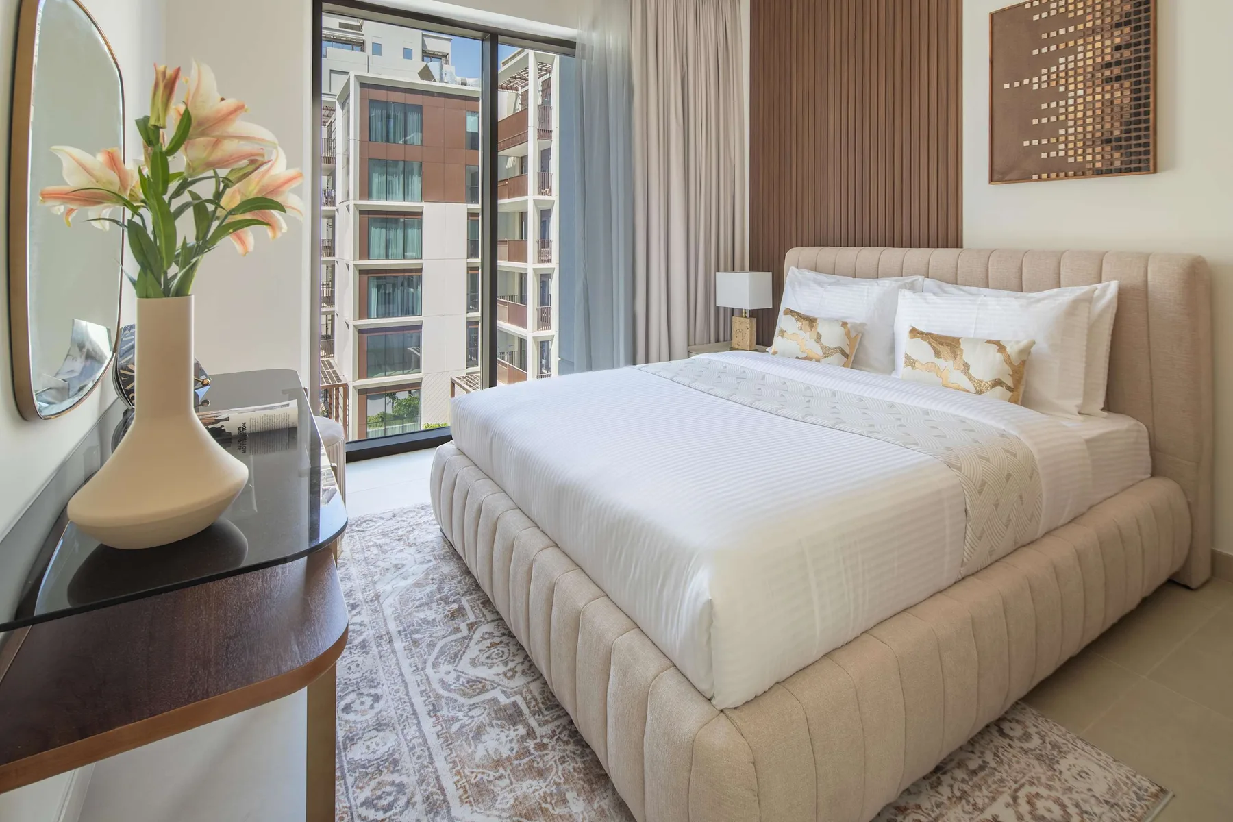 Un dormitorio con una cama bien tendida junto a una ventana grande.