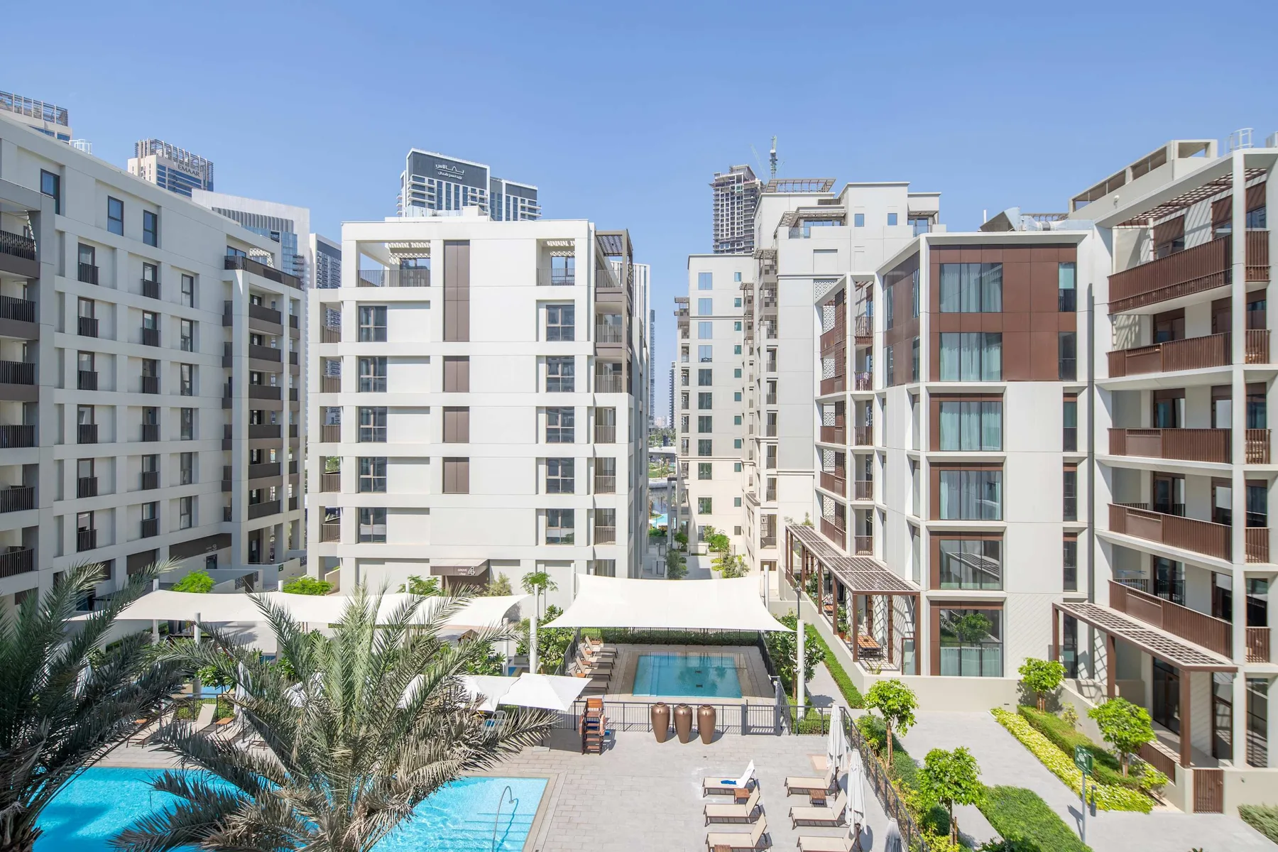 Edificios de apartamentos rodean una piscina al aire libre y un patio ajardinado.