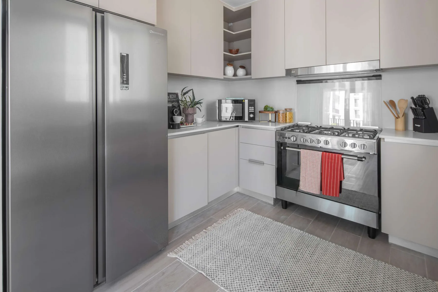 Una cocina moderna con gabinetes claros, un refrigerador y una estufa de acero inoxidable.