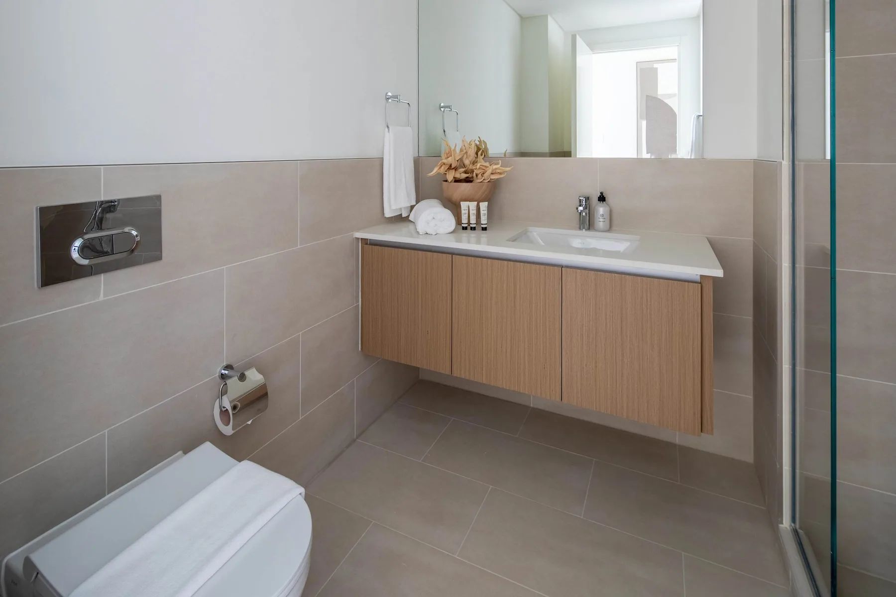 Un baño moderno con un lavabo suspendido, lavamanos e inodoro de pared.