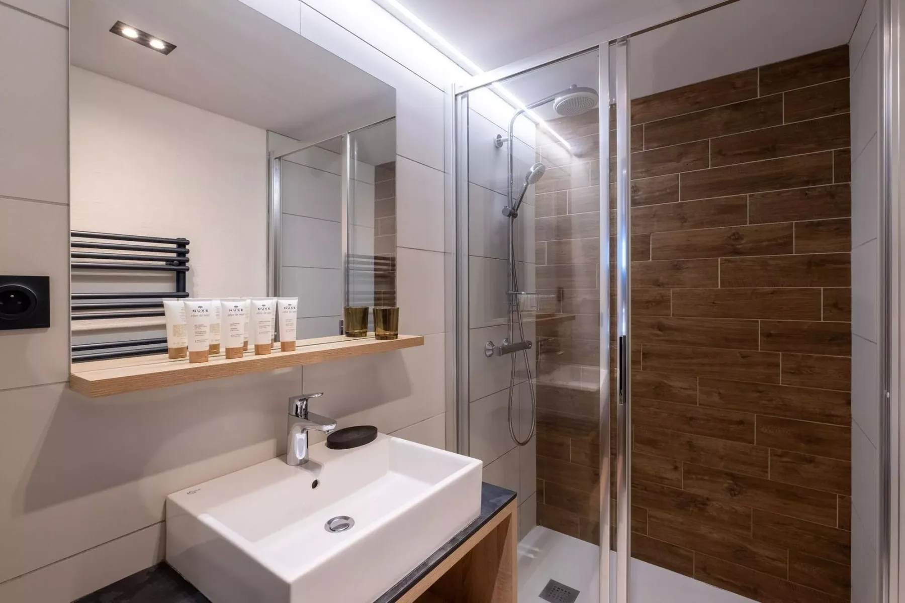 A modern bathroom with a sink beside a glass-enclosed shower.