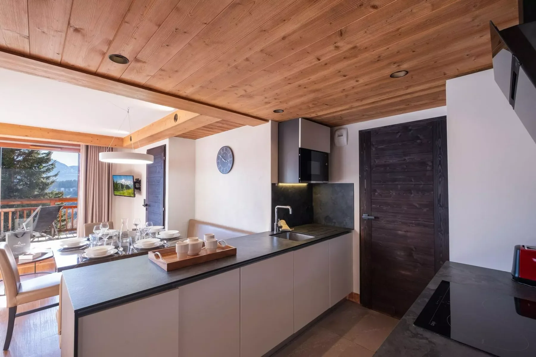 An open kitchen and dining area with a counter overlooking a balcony.
