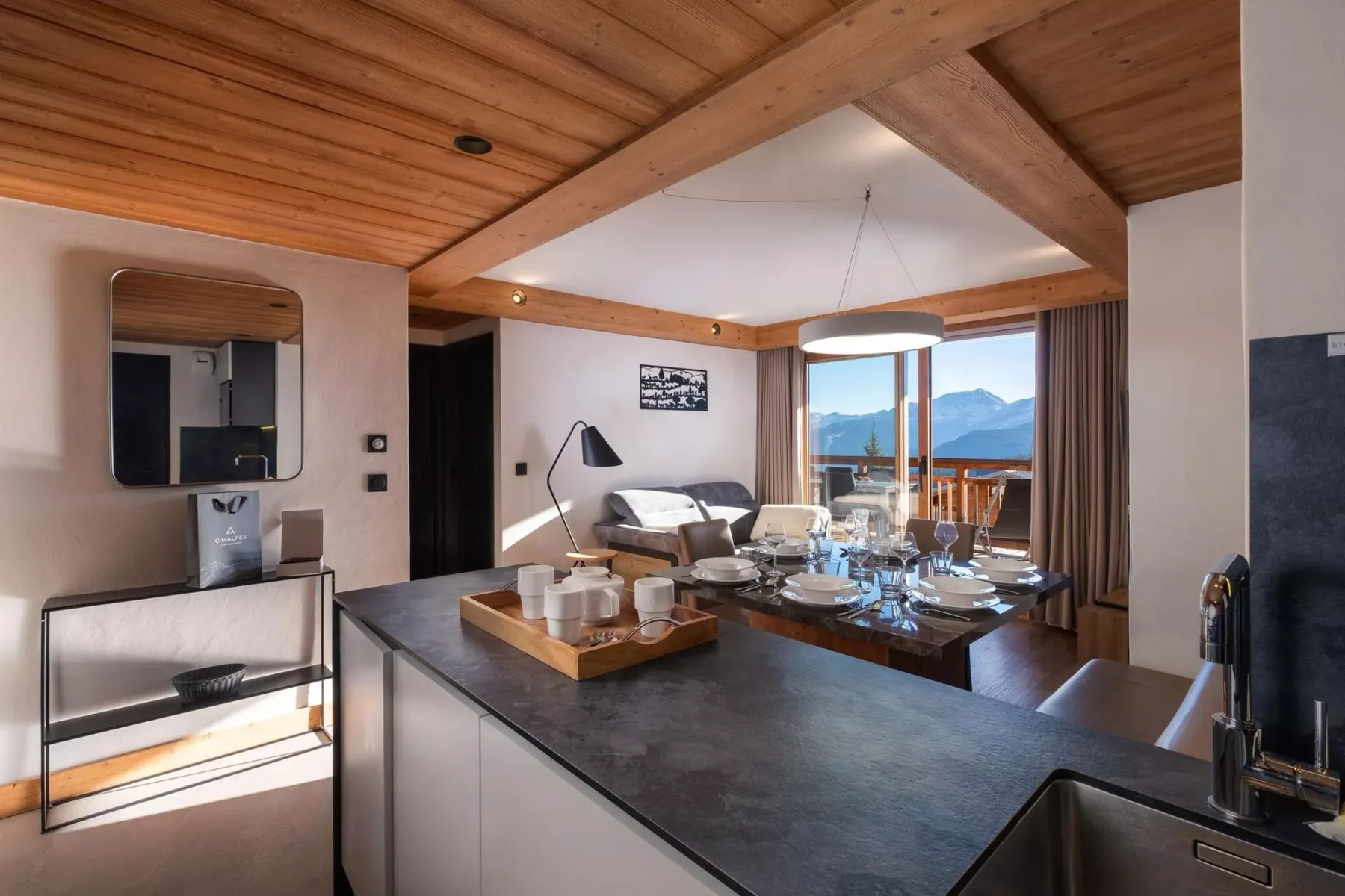 An open-plan kitchen and dining area with a table set beside a living space.