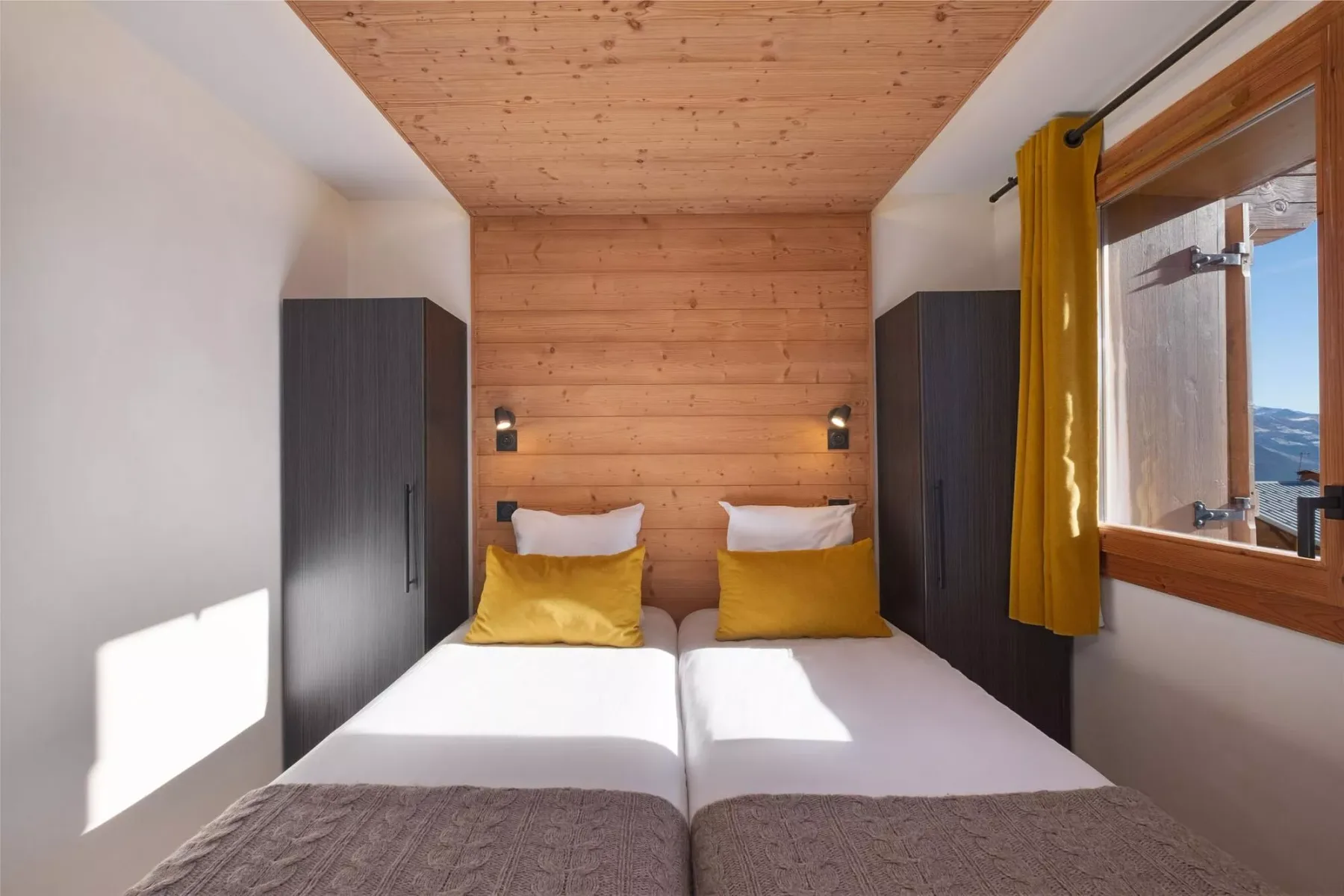 A bedroom with two single beds beneath a wood-paneled wall.