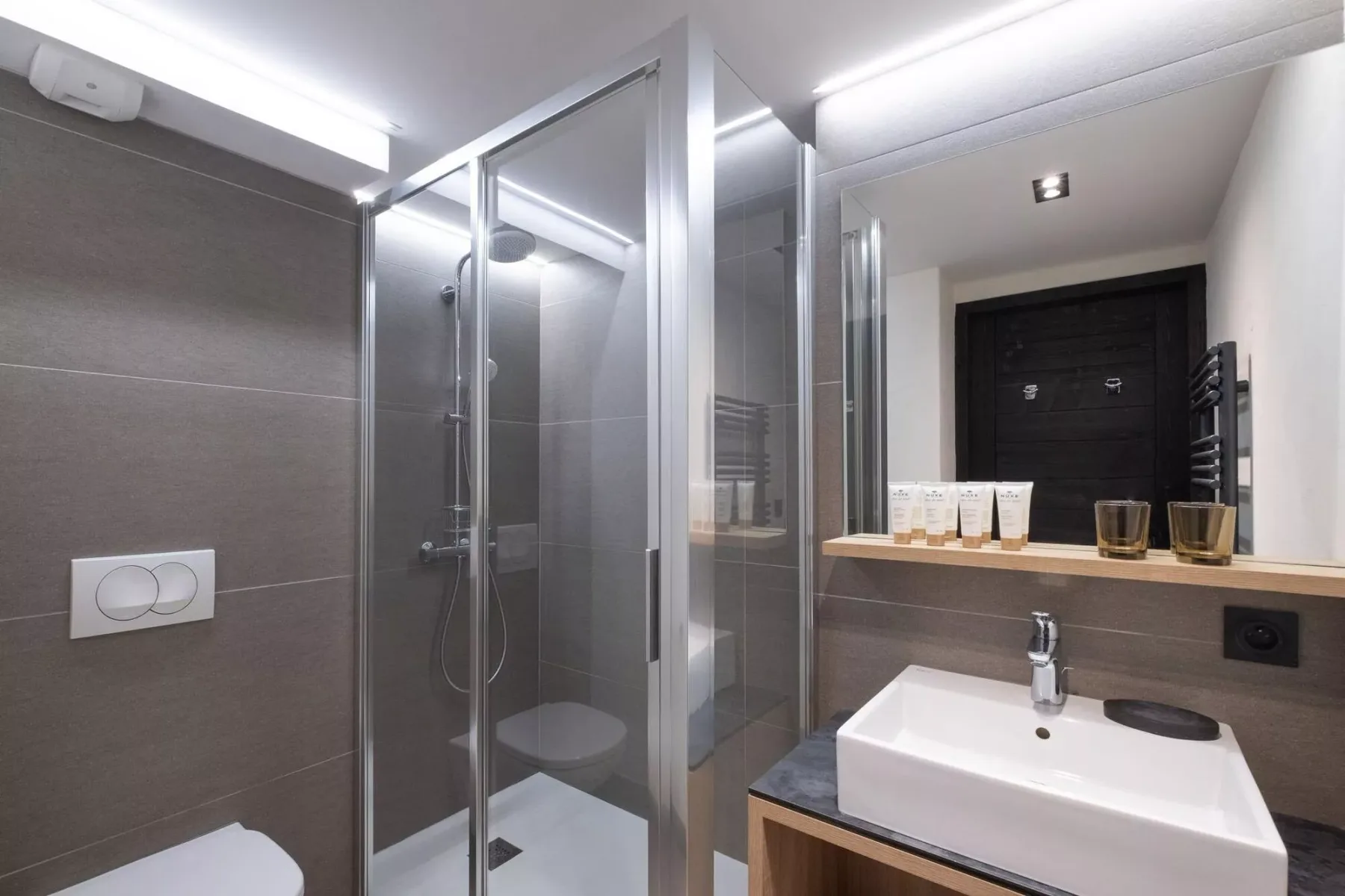 A modern bathroom with a glass shower and a white sink.