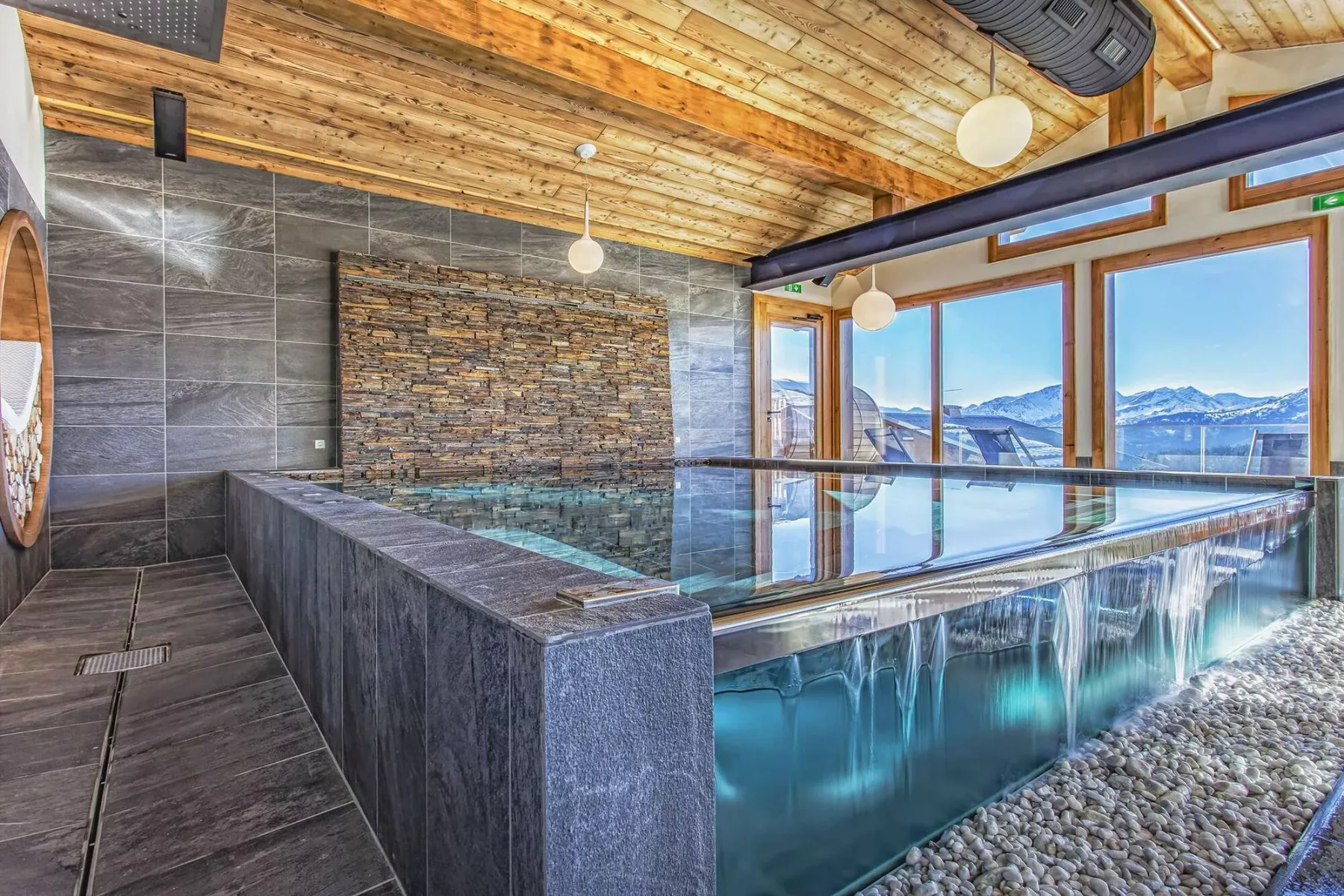 An indoor pool with large windows overlooking a mountain landscape.