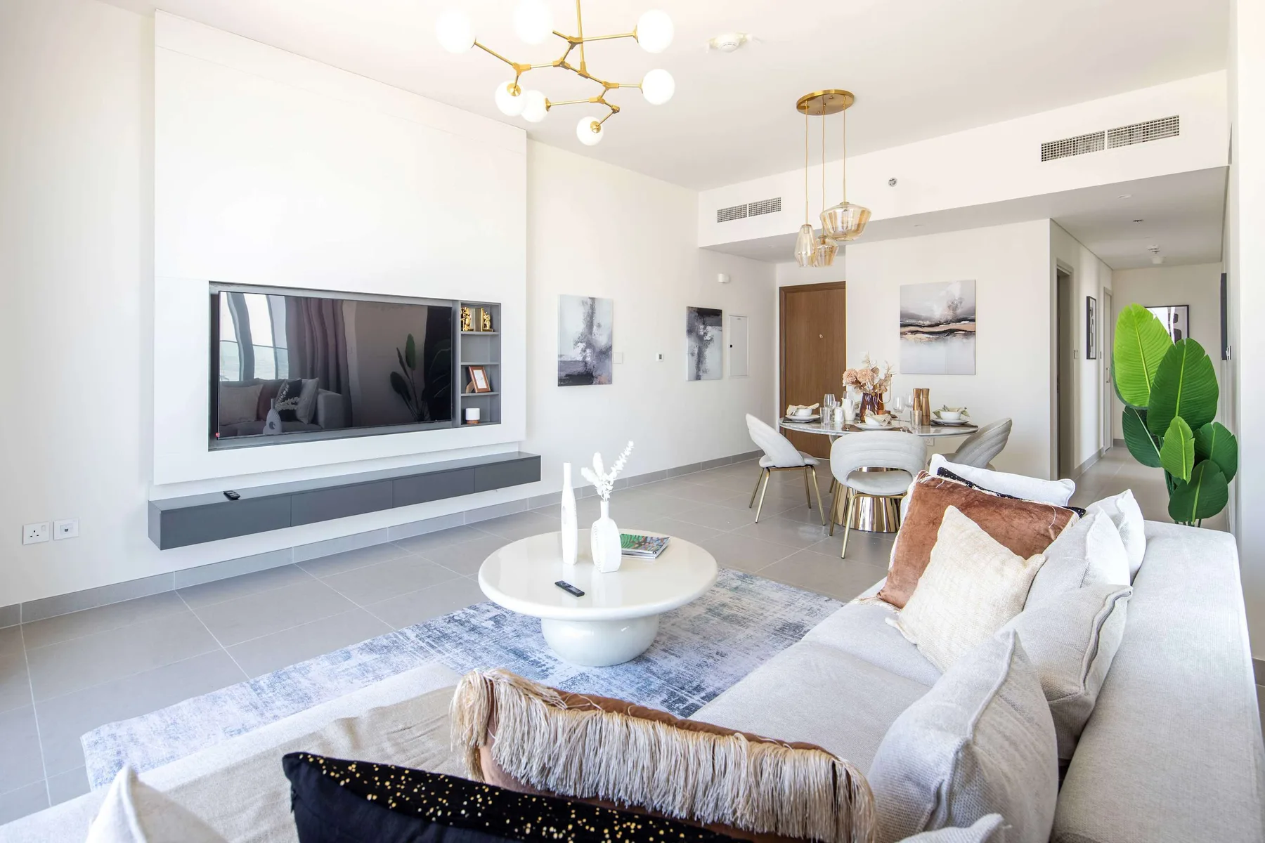 A bright living room with seating, a coffee table, and a dining area.
