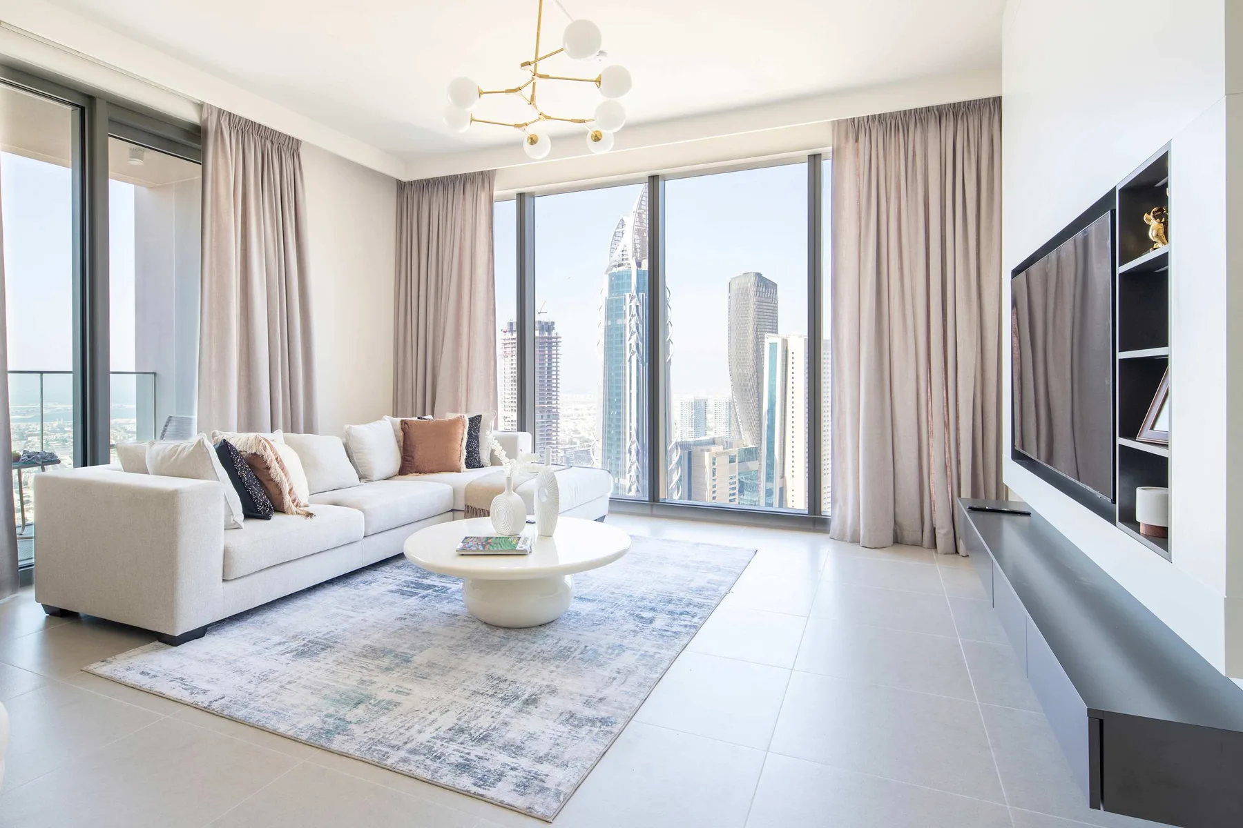 A bright living room with a sofa and large windows overlooking city buildings.