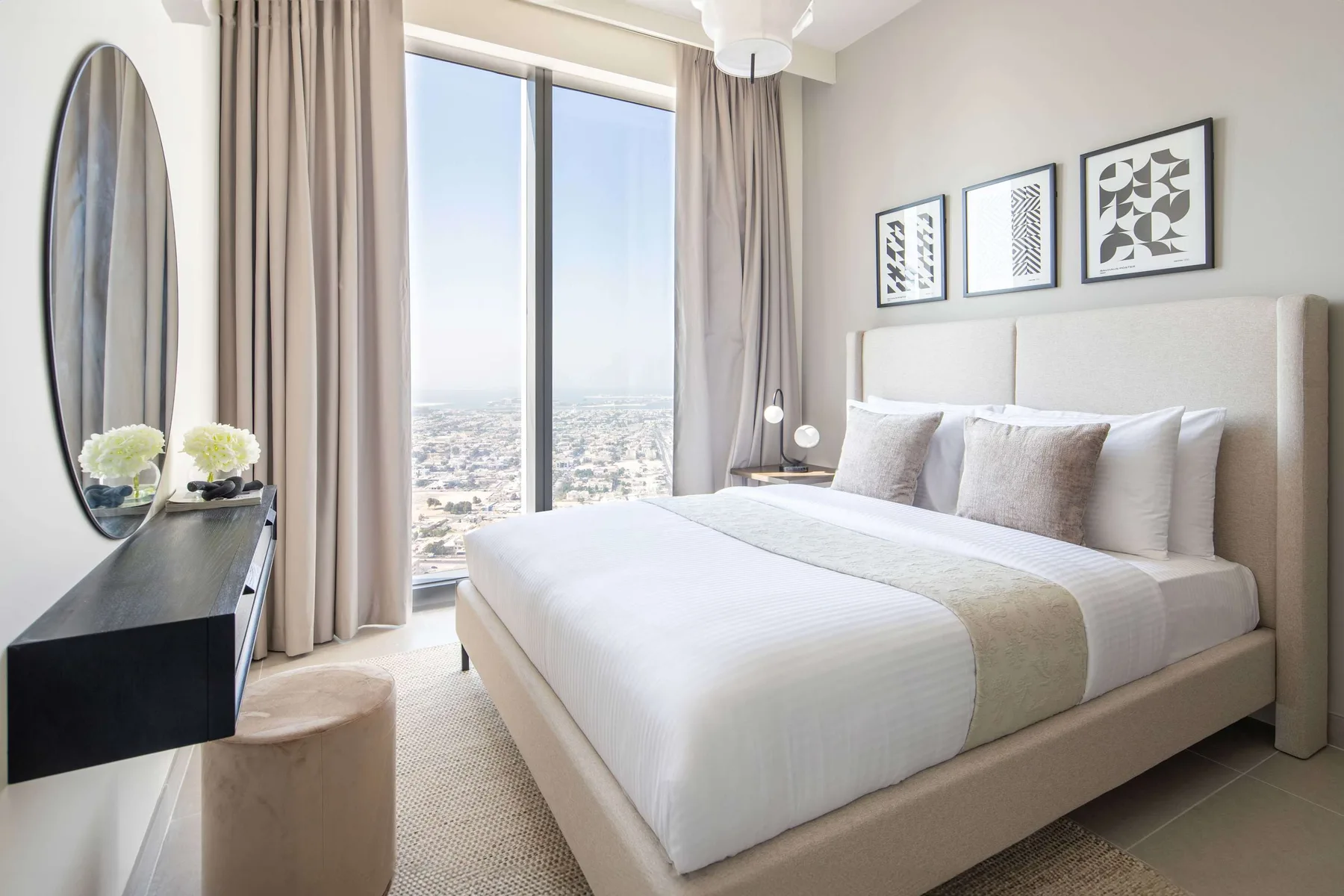 A bright bedroom with a neatly made bed beside a large window.