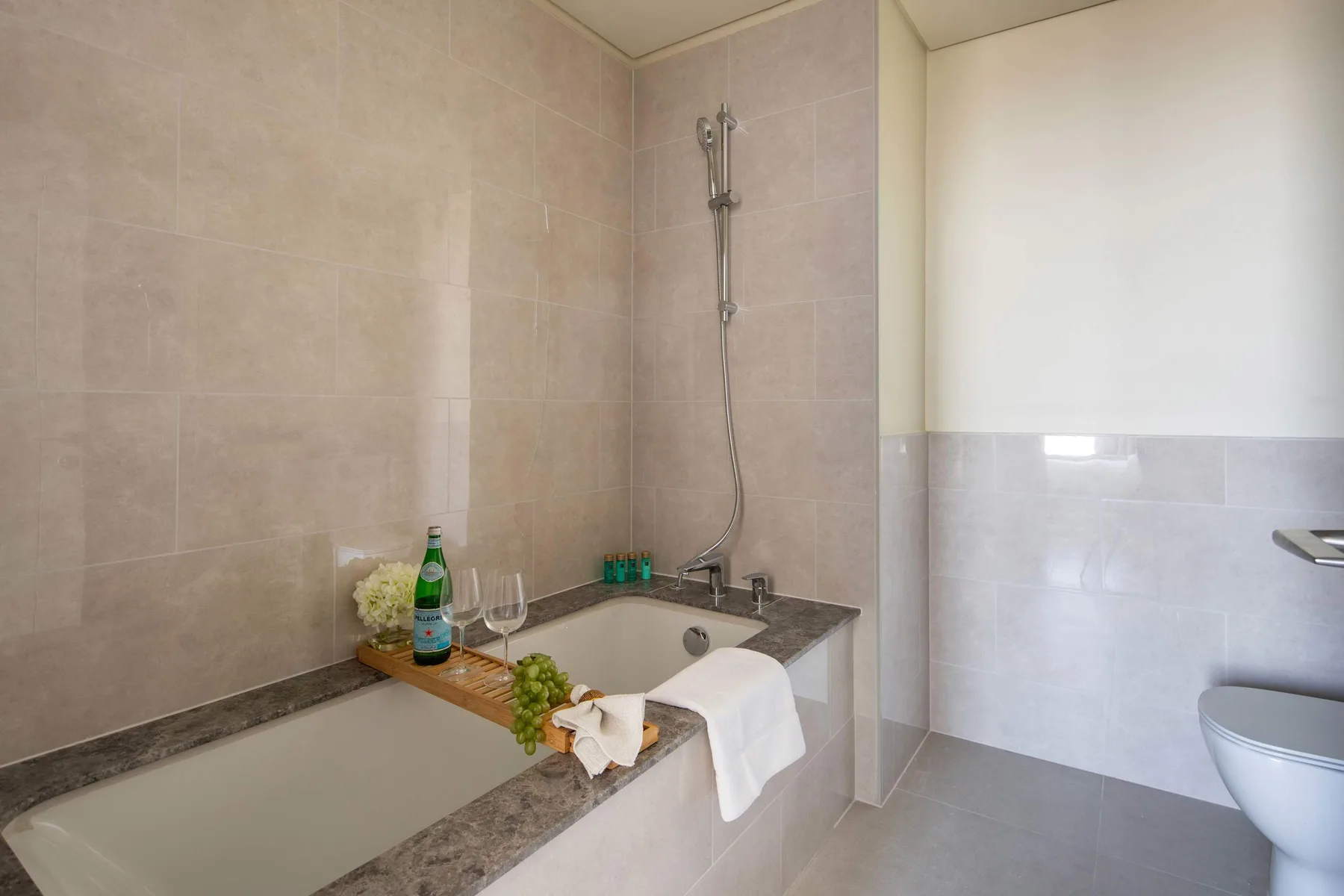 A tiled bathroom with a bathtub, shower, and folded towels.