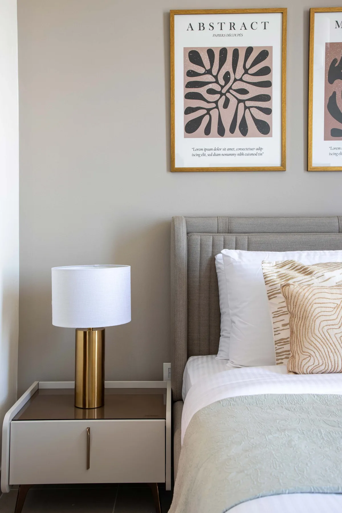A bedroom with a neatly made bed, bedside table, and framed wall art.