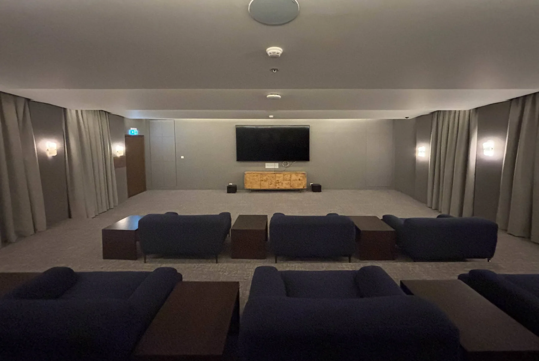 A screening room with rows of seating facing a large television.