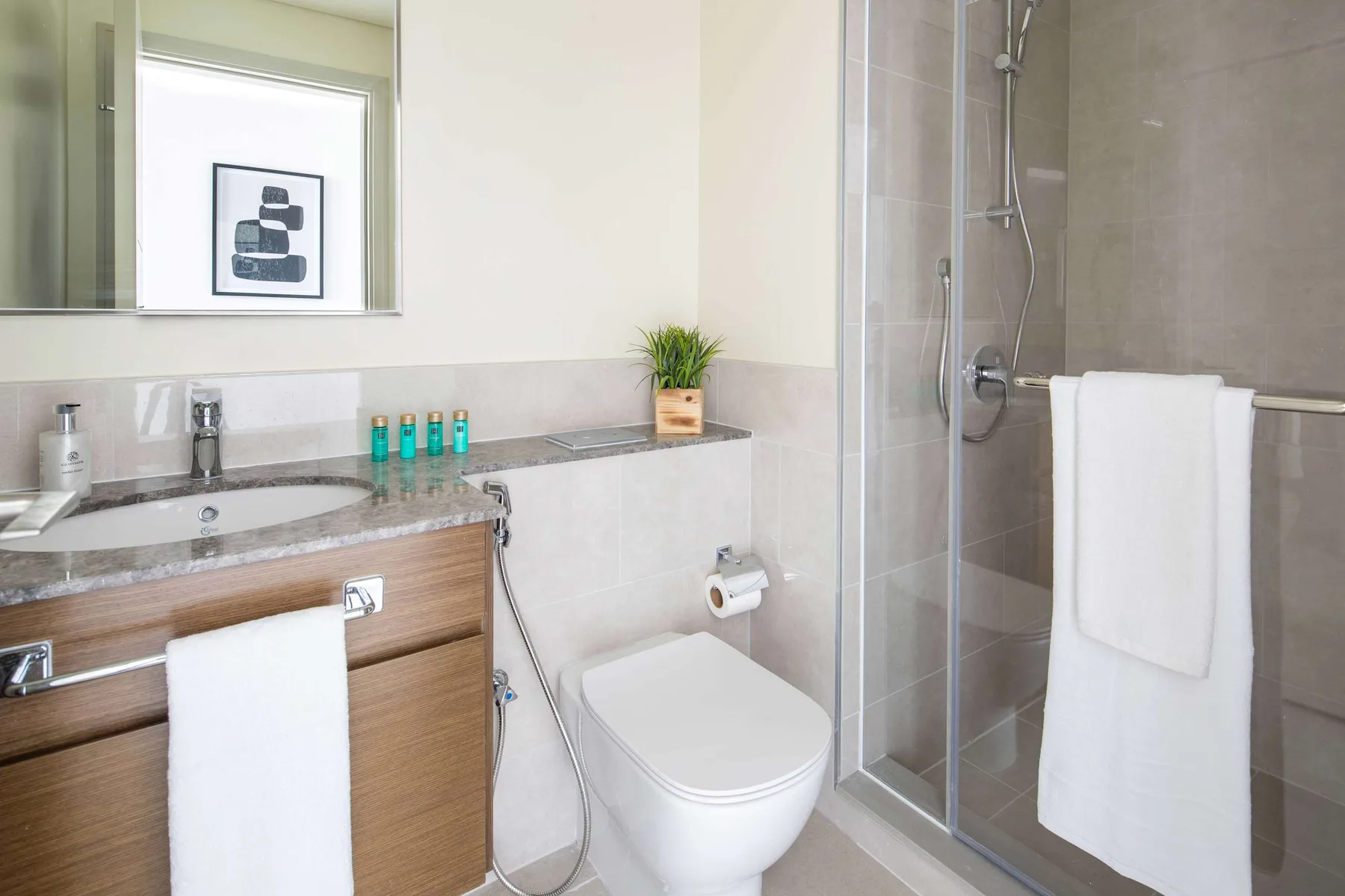 A bright bathroom with a vanity, toilet, and glass shower.