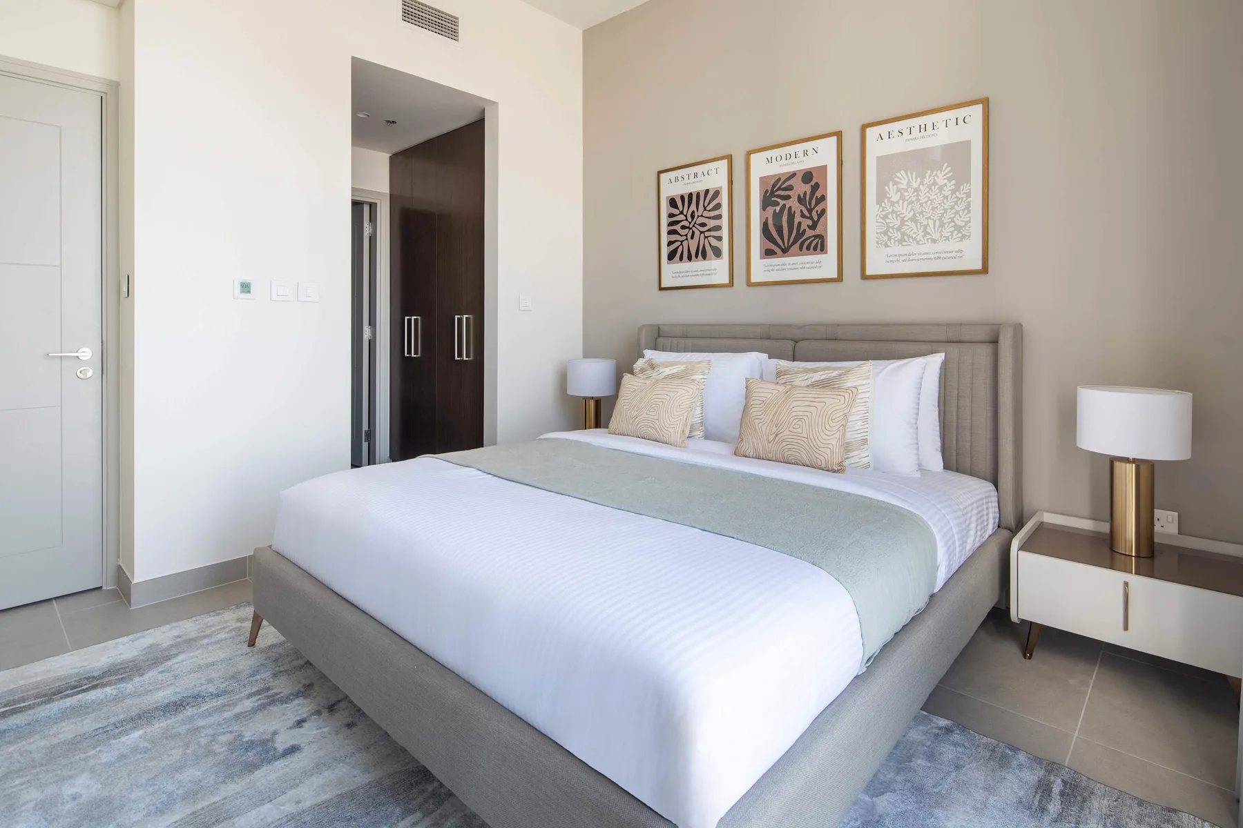 A bedroom with a large bed beneath three framed botanical prints.