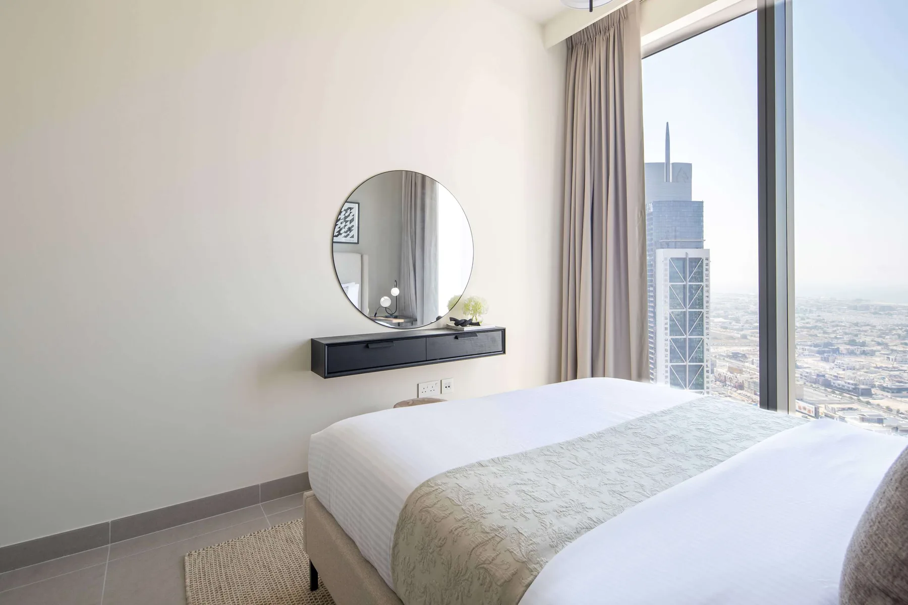 A bright bedroom with a neatly made bed beside a large window.
