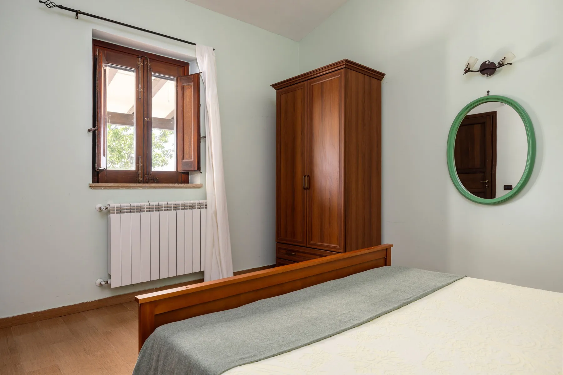 Un dormitorio con una cama de madera, un armario y una ventana.