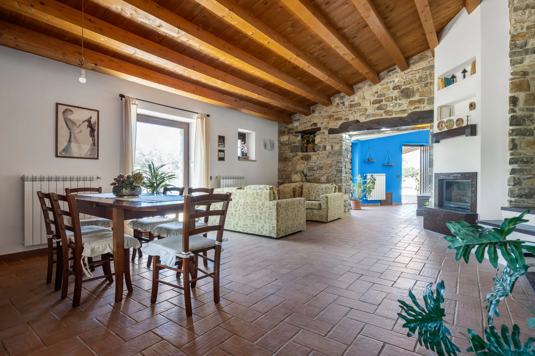 Una sala de estar y comedor con vigas de madera vistas y una pared de piedra.