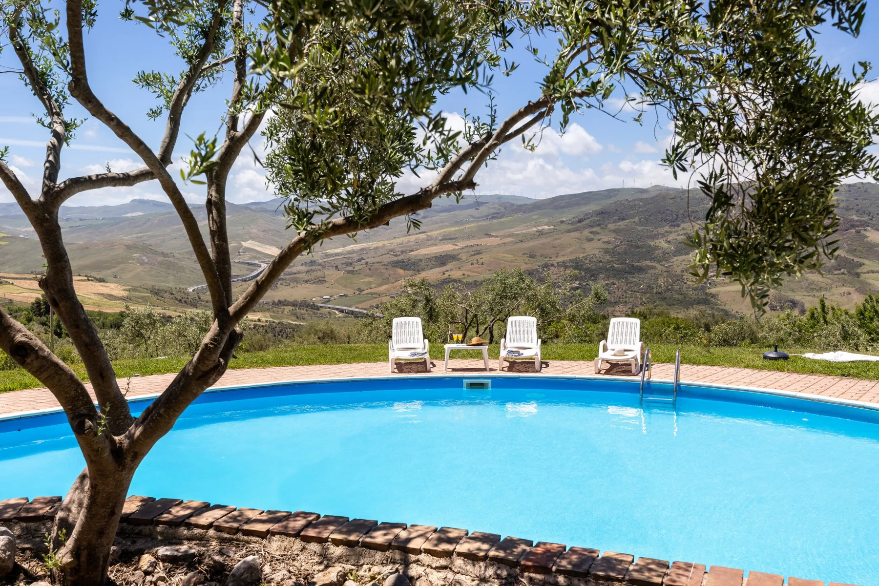 Una piscina al aire libre con asientos de descanso tiene vistas a un amplio paisaje rural.