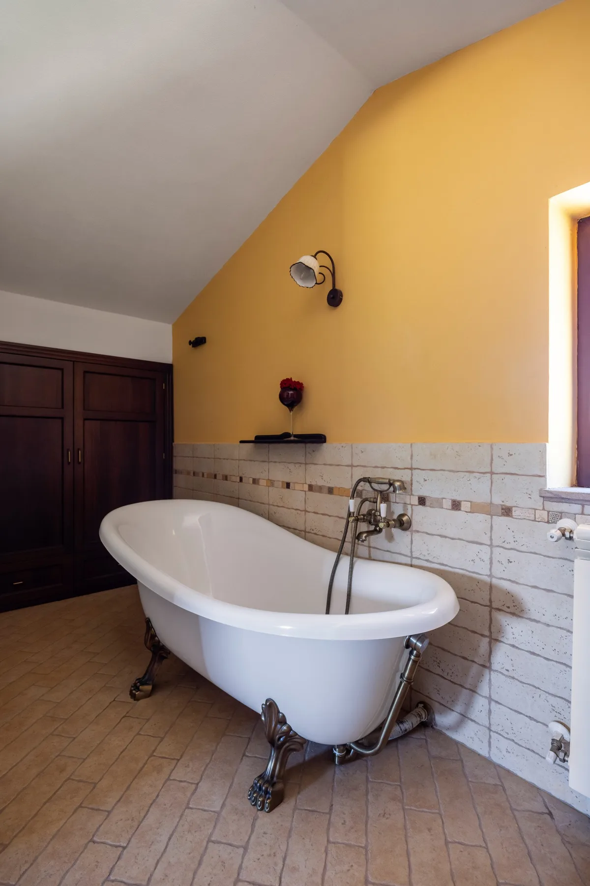 Un baño con una bañera exenta junto a una pared revestida de azulejos.