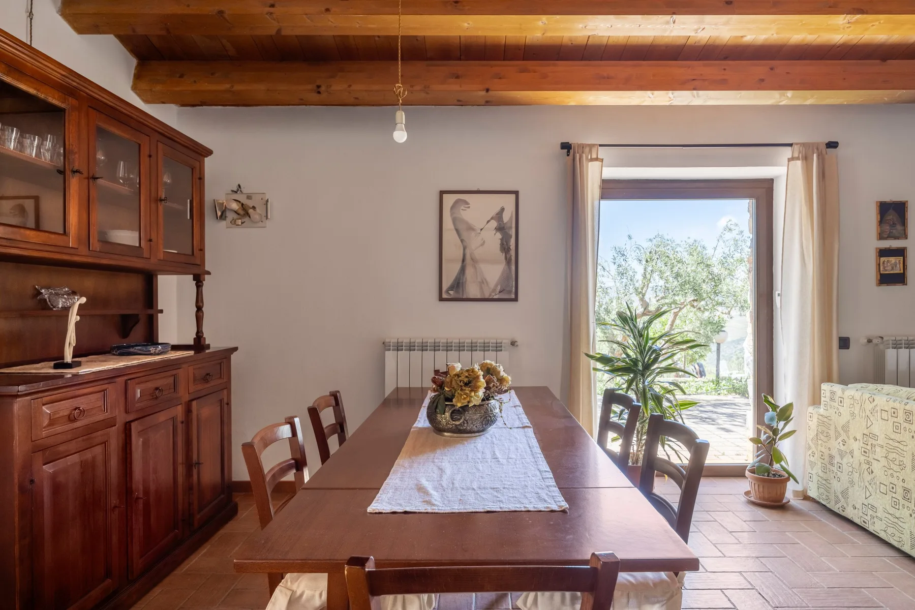 Un comedor con una larga mesa de madera y una gran ventana con vegetación a la vista.