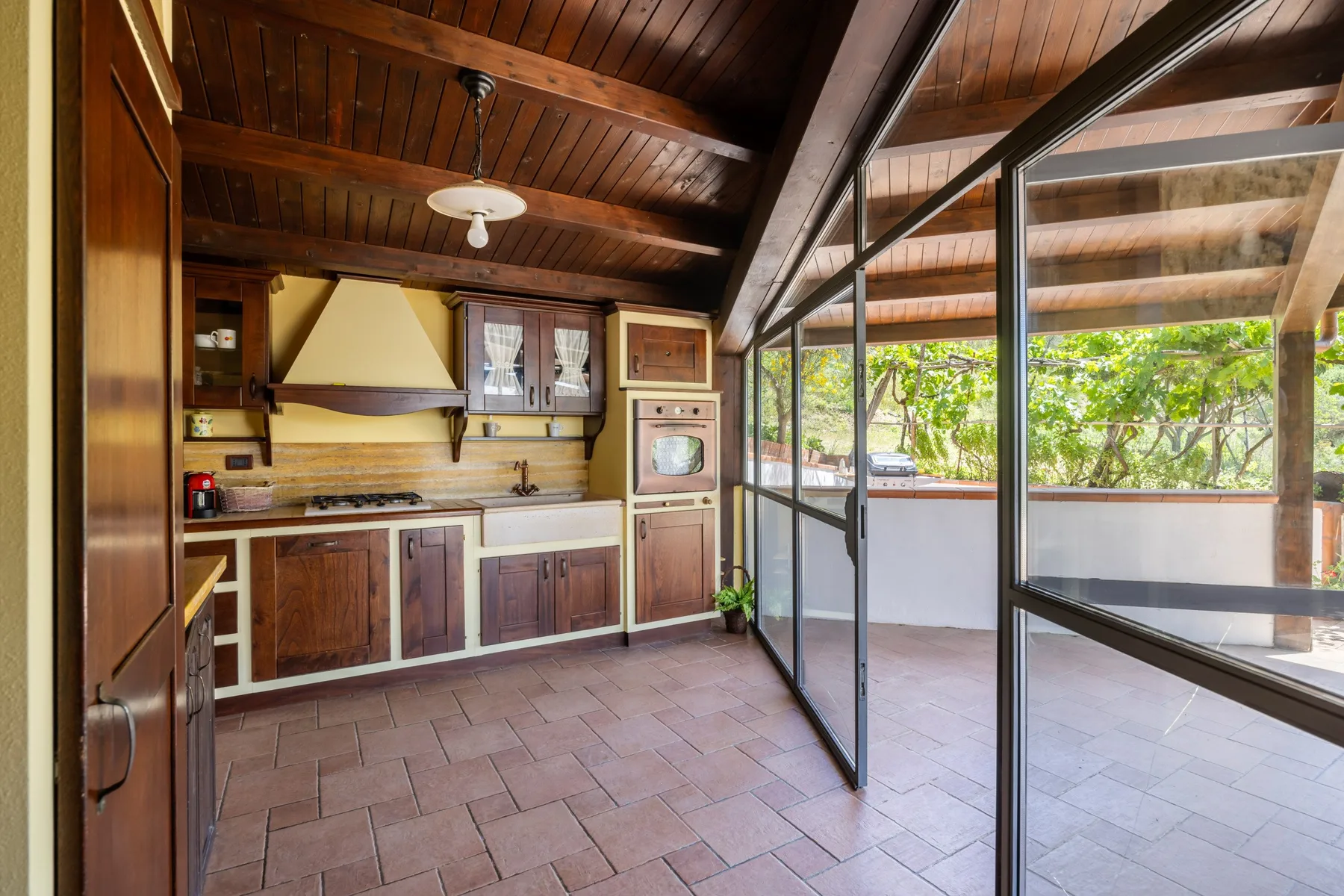 Una cocina con paneles de madera da a un patio embaldosado a través de puertas de vidrio.