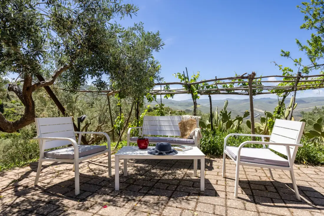Una zona de estar en un patio exterior con una mesa baja da a un paisaje verde.