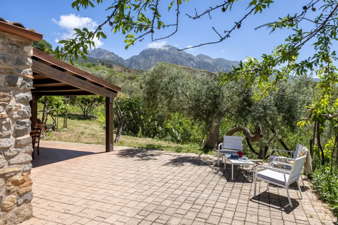 Un patio exterior pavimentado con asientos ofrece vistas a árboles y montañas lejanas.