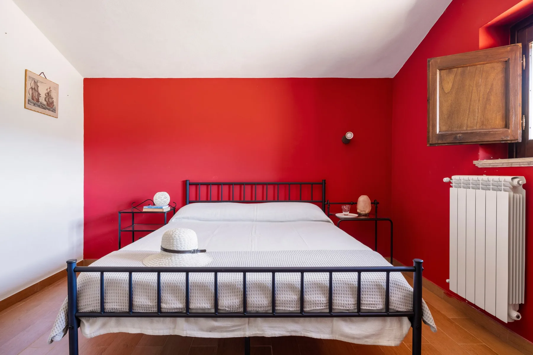 Un dormitorio con una cama junto a una pared roja y un radiador cerca.