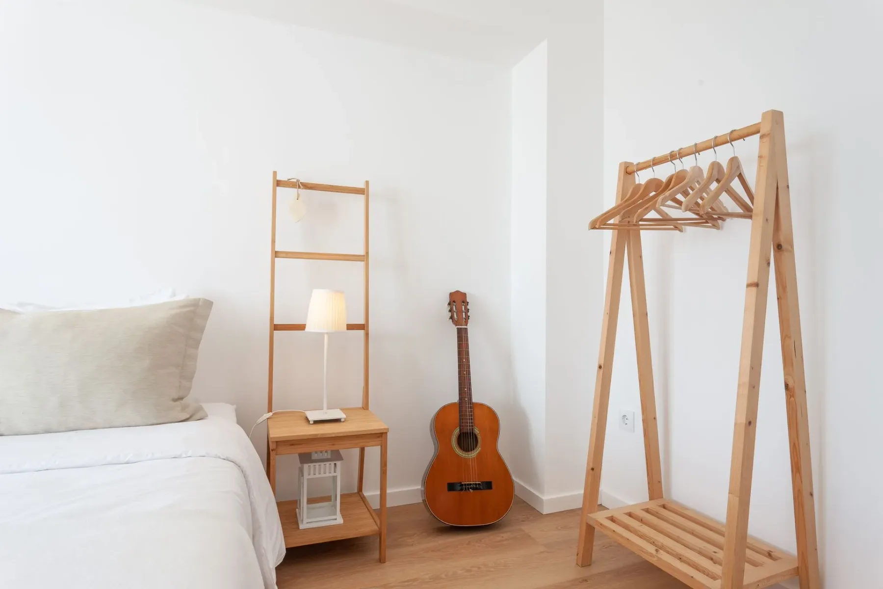 Dormitorio con una cama, mesa de noche, lámpara y guitarra