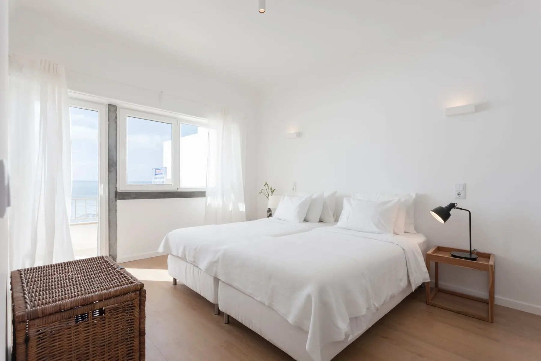 Dormitorio con dos camas, un baúl, una lámpara y una ventana