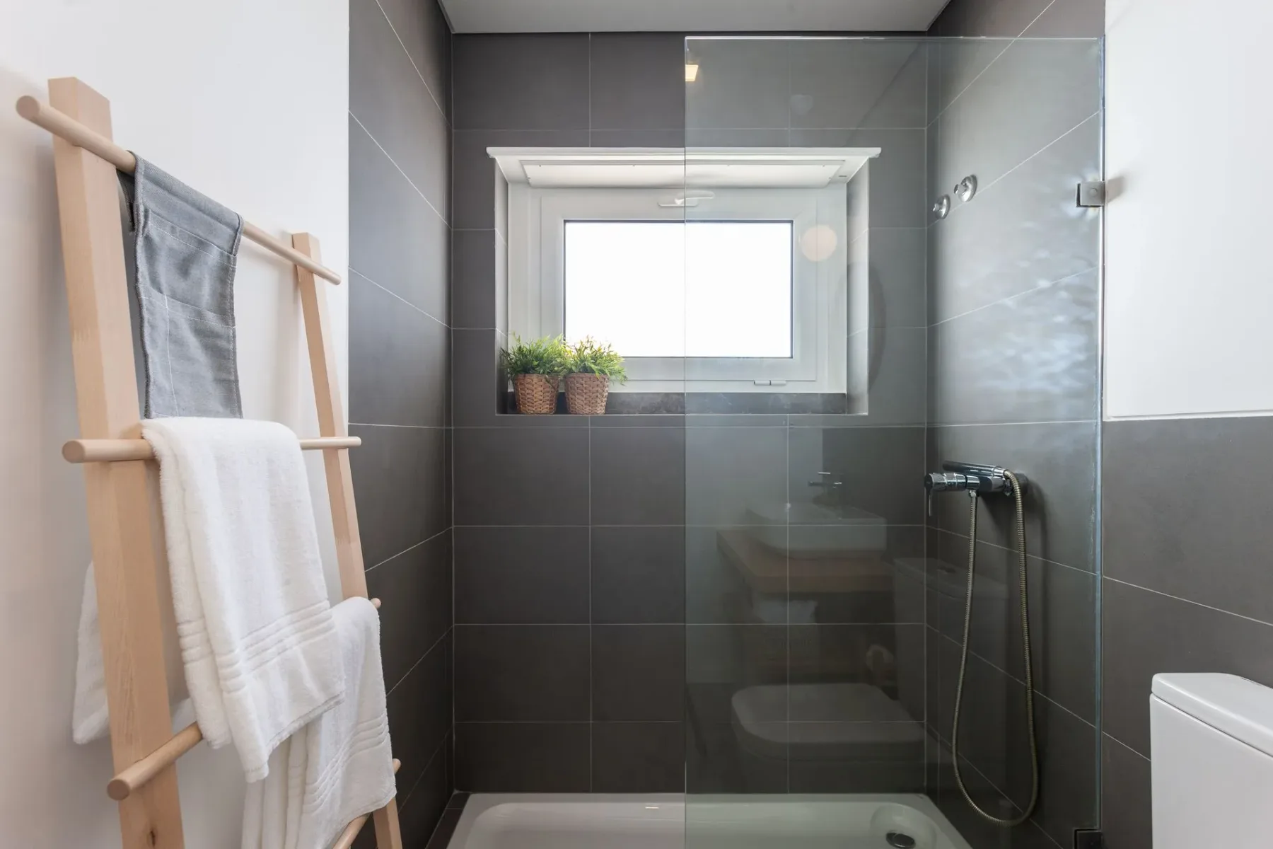 Baño con ducha a ras de suelo, lavabo, inodoro y ventana