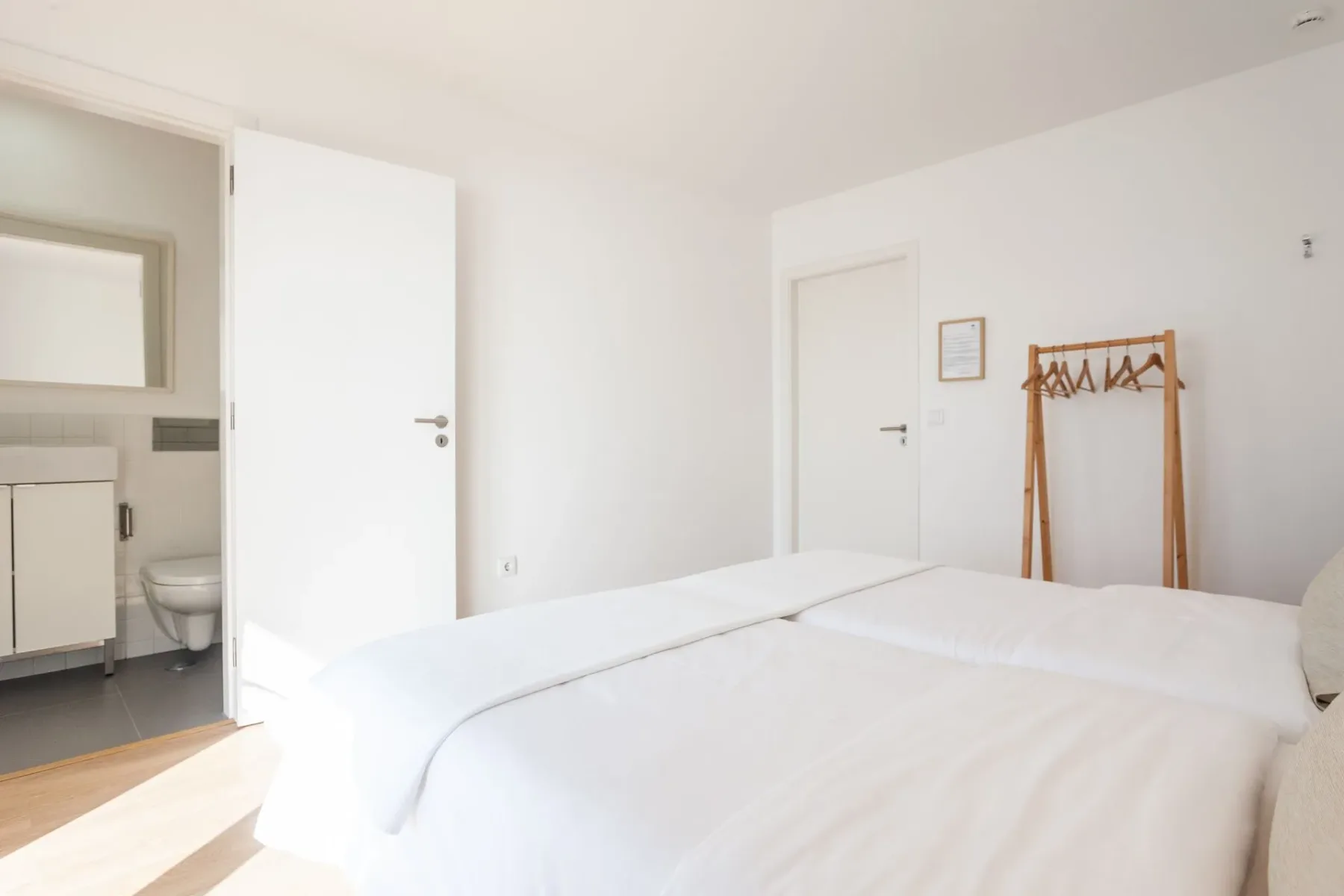 Habitación con una cama, espejo y perchero