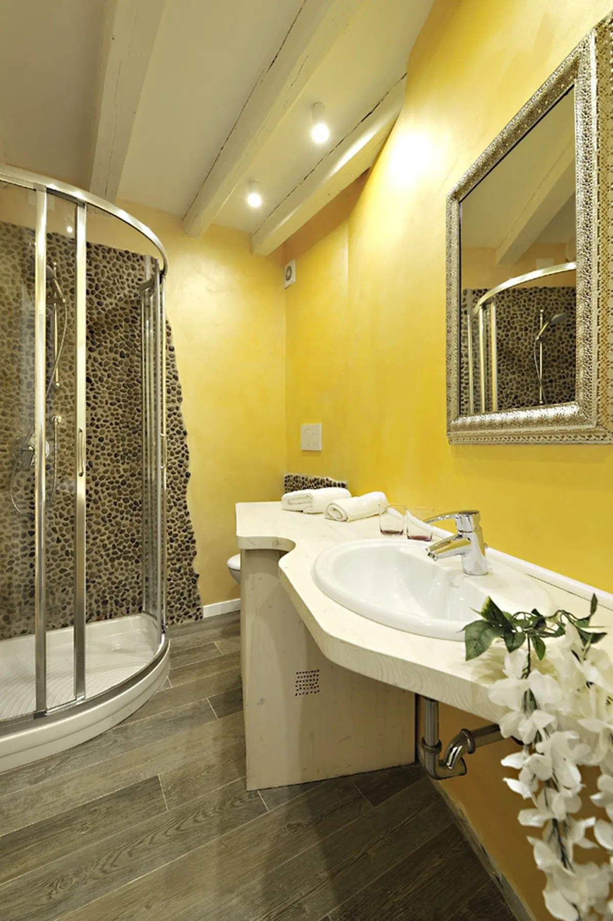 A bright bathroom with a curved shower enclosure and a sink beneath a mirror.