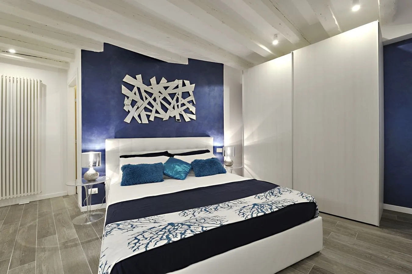 A bedroom with a bed dressed in blue and white bedding.