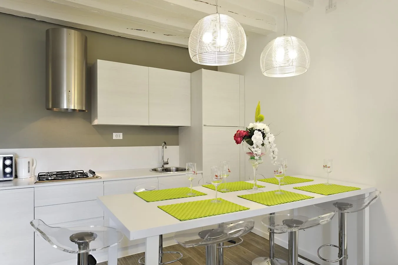A bright kitchen with a white island set with green placemats and flowers.