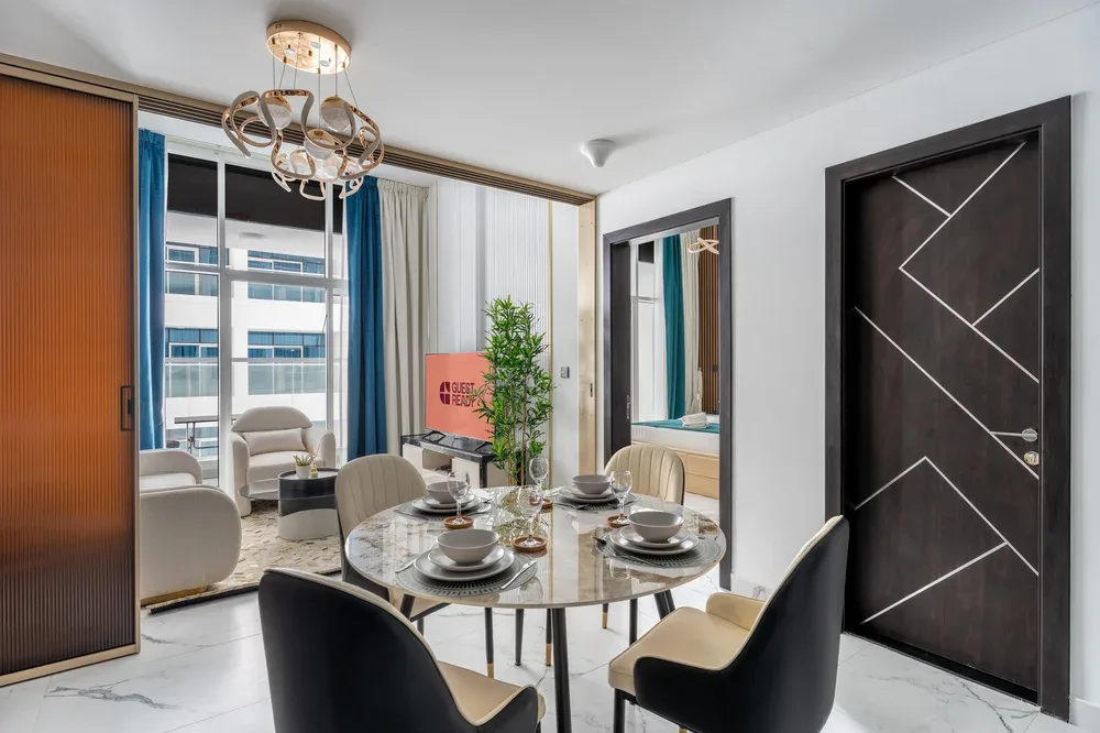 Comedor con una mesa redonda y sillas junto a grandes ventanas.