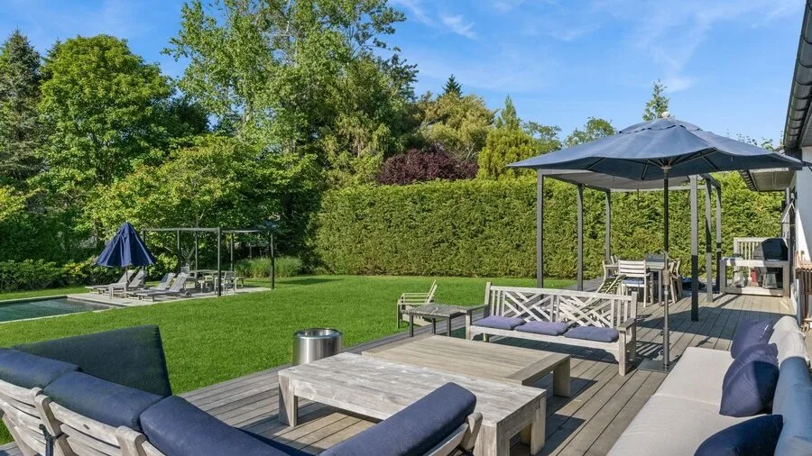 A landscaped garden patio with outdoor seating and a large shade umbrella.