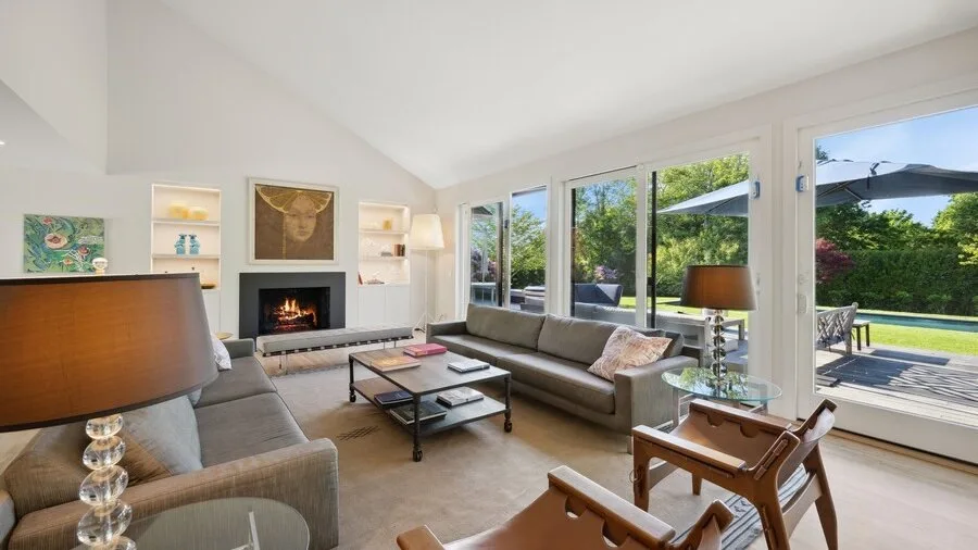 A bright living room with seating arranged around a coffee table beside large windows.