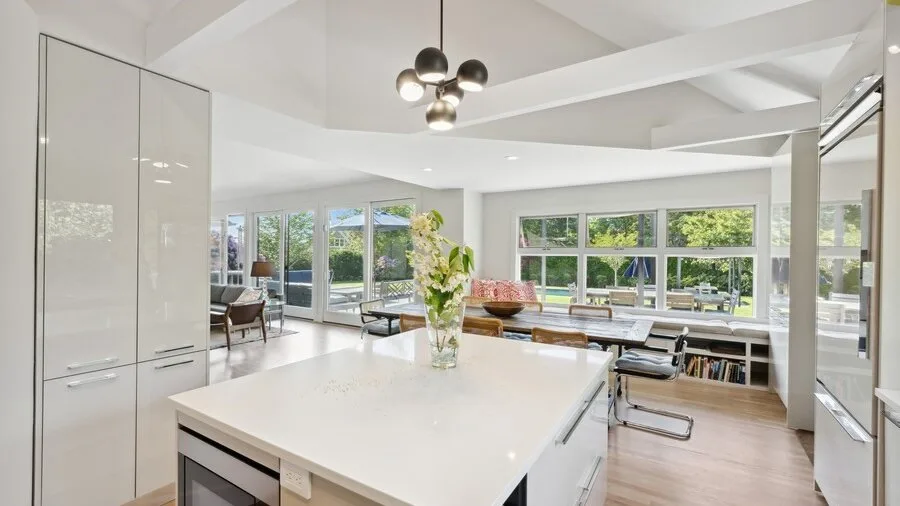 A bright open-plan kitchen and dining area with a large island and wide windows.