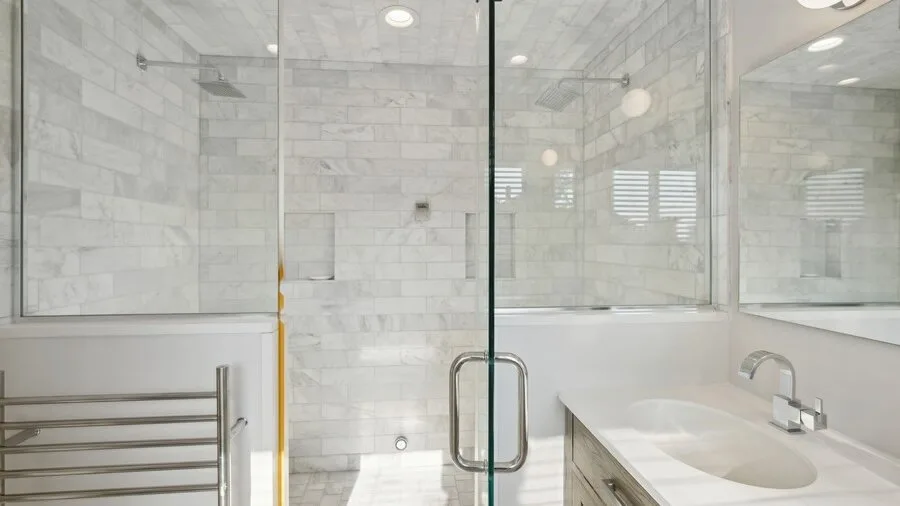 A tiled bathroom with a glass shower and a white sink.