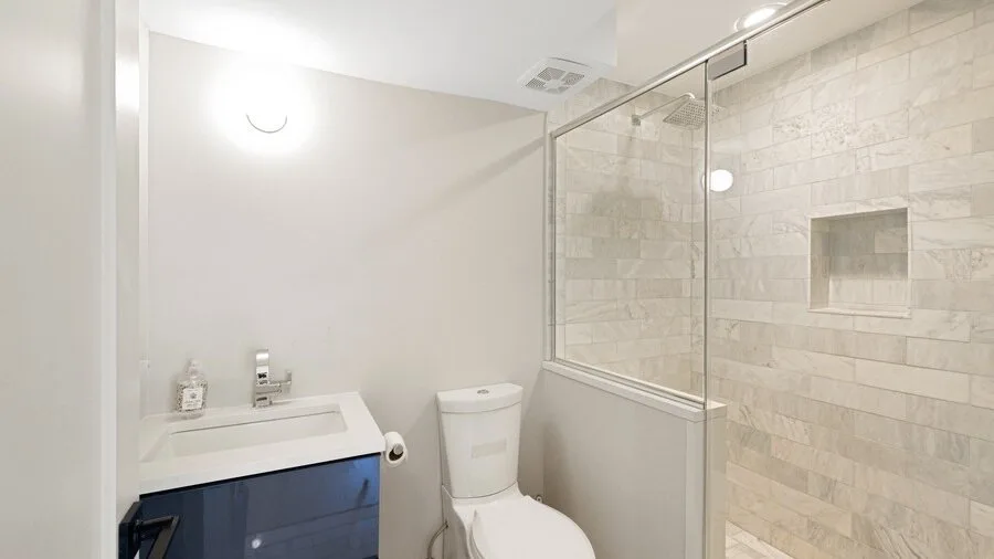 A bathroom with a sink, toilet, and glass-enclosed shower.